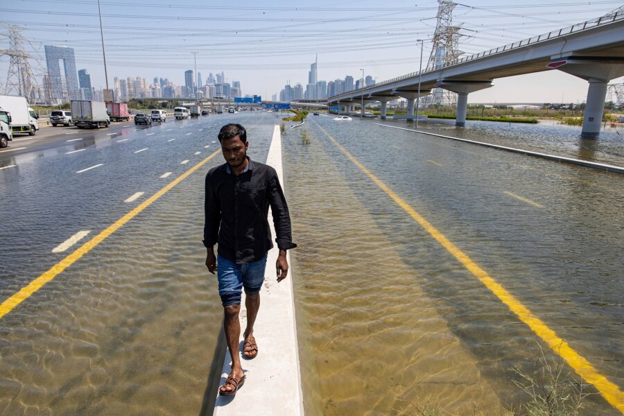 Bilder des Tages vom 18.04.2024 - In den Vereinigten Arabischen Emiraten hat sich der heftigste Regen seit Jahrzehnten ereignet und Teile der Metropole Dubai überschwemmt. Ein Mann geht entlang einer Straßensperre auf der Sheikh Zayed Road.