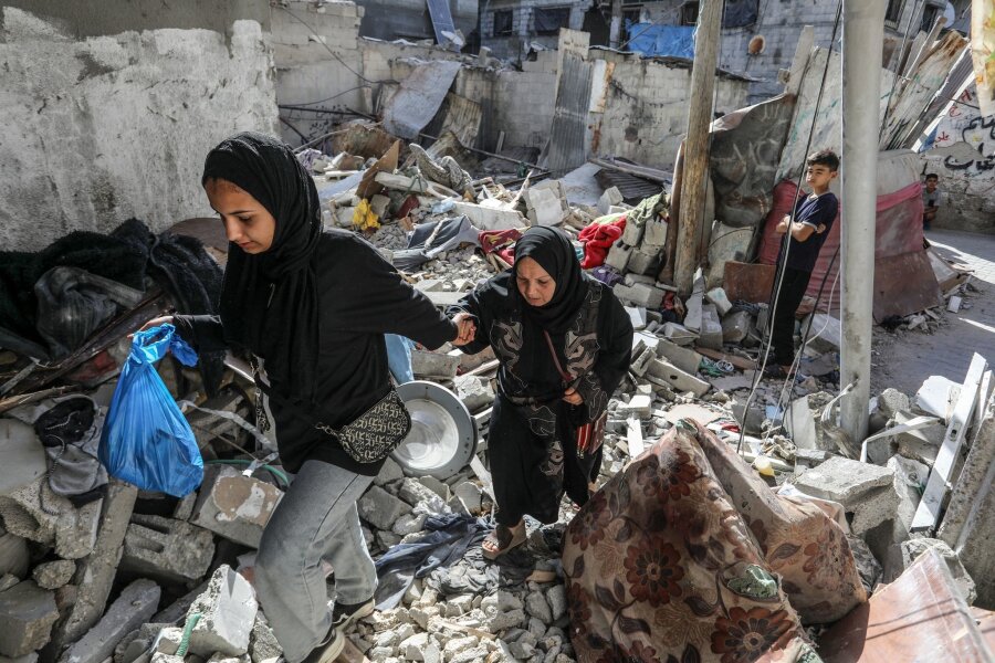 Bilder des Tages vom 18.06.2024 - Bilder der Verwüstung: Zwei Palästinenserinnen gehen durch die Trümmer, die ein israelischer Luftangriff hinterlassen hat. Bei dem Angriff kamen mindestens zehn Menschen ums Leben.