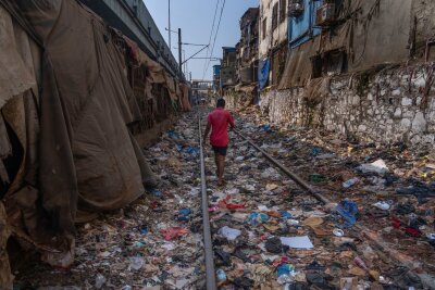 Bilder des Tages vom 22.04.2024 - Ein Mann geht am Tag der Erde über ein mit Plastik und anderen Abfällen übersätes Bahngleis in Mumbai.