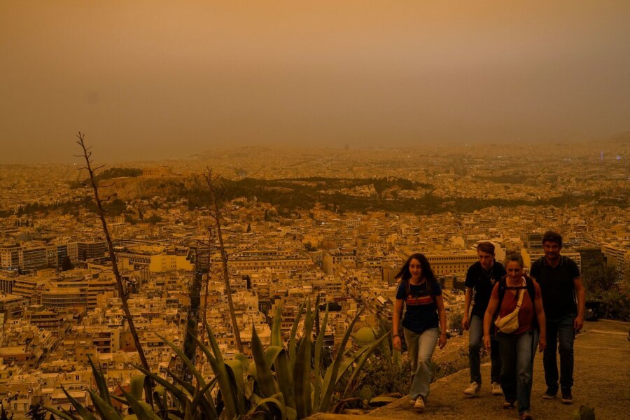 Bilder des Tages vom 23.04.2024 - Touristen spazieren auf dem Lycabettus-Hügel in Athen, während der Himmel über der griechischen Hauptstadt mit dem antiken Akropolis-Hügel im Hintergrund infolge von Saharastaub eingetrübt ist.