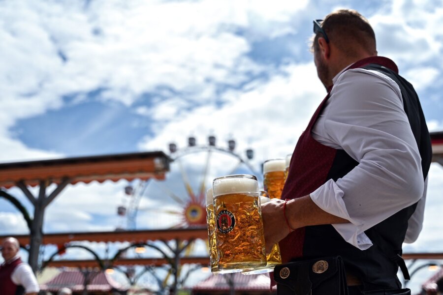 Bilder des Tages vom 26.04.2024 - Sonne auf dem Frühlingsfest: Nach einigen Tagen des typischen Aprilwetters werden die Getränke auf dem Münchner Volksfest wieder bei Sonne serviert.