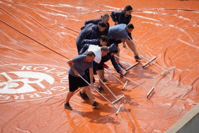 Bilder des Tages vom 26.05.2024 - Mitarbeiter der French Open beseitigen Regenwasser von einer Abdeckung. Starke Regenschauer haben bei dem bekannten Tennisturnier in Paris für Unterbrechungen gesorgt.