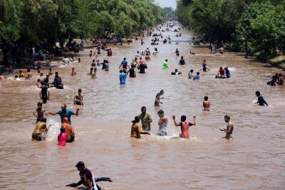 Bilder des Tages vom 26.05.2024 - Badespaß: Menschen kühlen sich bei heißem Wetter in einem Kanal in der pakistanischen Megacity Lahore ab. In vielen Städten des Landes herrscht derzeit eine Hitzewelle.