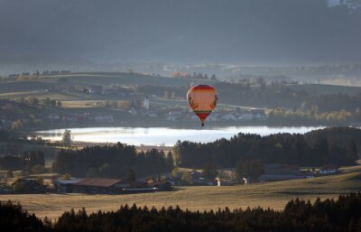 Bilder des Tages vom 27.04.2024 - Ein Heißluftballon gleitet über den Hopfensee im Allgäu.