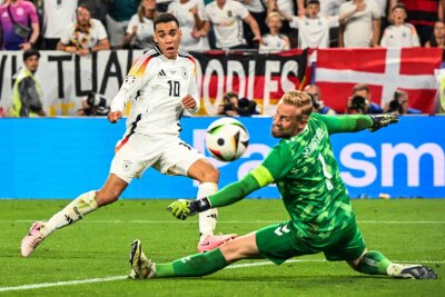 Bilder des Tages vom 29.06.2024 - Der geht rein... Deutschlands Jamal Musiala (l) trifft im EM-Achtelfinale gegen Dänemarks Torhüter Kasper Schmeichel zum 2:0. Die deutsche Mannschaft hat sich fürs Viertelfinale qualifiziert.