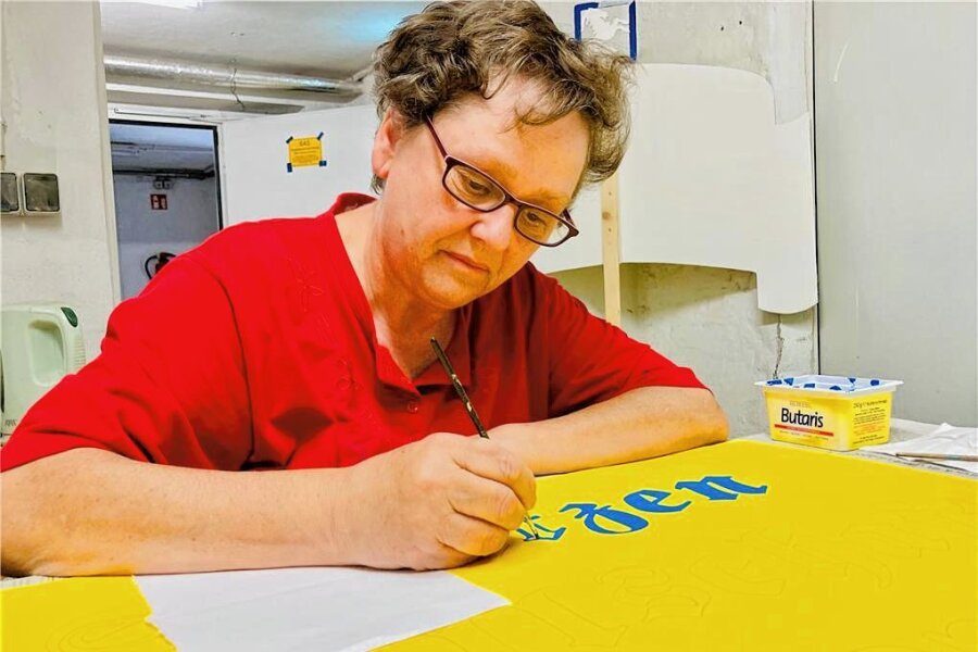 Bockau feiert 50 Jahre Wurzelfest – und begibt sich auf die Socken - Andy Krehan setzt den Pinsel konzentriert an. Die 55-Jährige bringt die Schilder für den Festumzug zum 50. Wurzelfest in Bockau auf Vordermann.