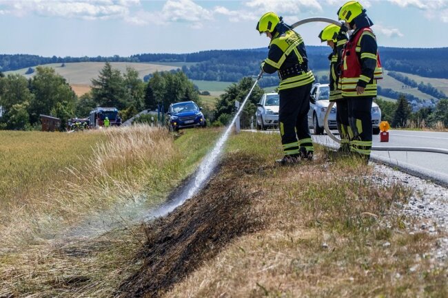 Feuerwehrleute löschen die bei Meinersdorf brennende Böschung. Passanten konnten zuvor bereits eine weitere Ausbreitung verhindern. 