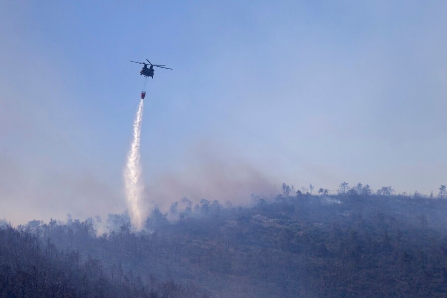 Brand im Norden Athens gelöscht – Brandgefahr bleibt hoch - Ein Hubschrauber wirft Wasser auf einen Waldbrand im Norden Athens ab.