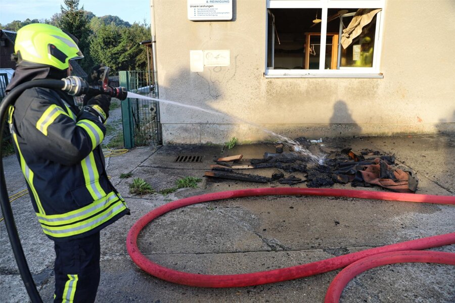 Brand in einer Wäscherei in Schwarzenberg: Feuerwehr verhindert größeren Schaden - Aus dem Brandraum geholte, verkohlte Materialien, darunter Holzteile und Bodenmatten, wurden vor dem Wäschereigebäude noch abgelöscht.