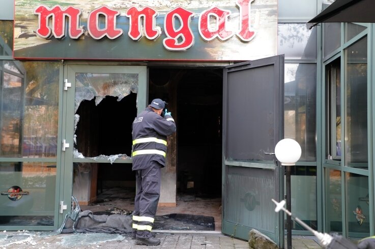 Am Morgen nach dem Feuer: Ein Beamter der Polizei dokumentiert vom Eingang des ausgebrannten Restaurants aus den Tatort. 