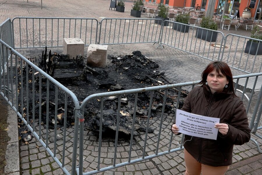 Stadtbibliothek-Leiterin Adriana Bellmann kurz nach der Brandstiftung vor den Resten des Bücherschrankes.