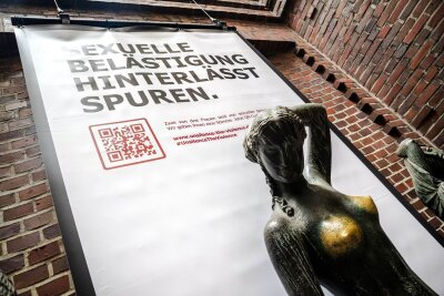 Bronze-Statuen als Zeichen gegen sexuelle Belästigung - Plakat mit der Aufschrift "Sexuelle Belästigung hinterlässt Spuren" hinter der Bronzeskulptur "Jugend" von Bernhard Hoetger in Bremen.