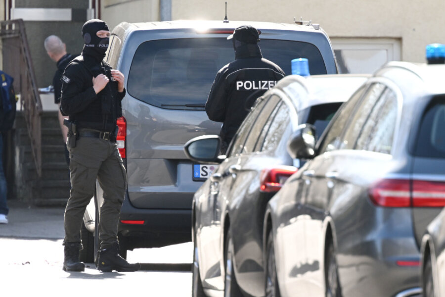 Bundesweite Razzien im "Reichsbürger"-Millieu: Ein Verdächtiger aus Chemnitz - Einsatzkräfte der Polizei stehen an Einsatzfahrzeugen. Bei einer Durchsuchung im Auftrag der Bundesanwaltschaft ist im baden-württembergischen Reutlingen ein Beamter eines Spezialeinsatzkommandos (SEK) durch einen Schuss verletzt worden. 