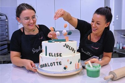 Bunt, süß, individuell: So teuer sind Torten zum Schulanfang in Chemnitz - Siselia Mädler (links) und Janette Graf von der Firma "Einzelstücke" bei den letzten Dekorationsdetails für eine Torte zum Schulanfang. 