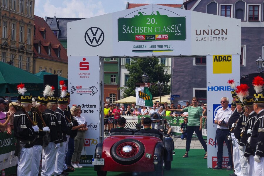 Cabrios bei der „Sachsen Classic“: Wie die Fahrer mit Regen umgehen - Oberbürgermeisterin Constance Arndt (BfZ) schickt die ersten Teilnehmer mit der Flagge des Freistaates Sachsen auf die Strecke.