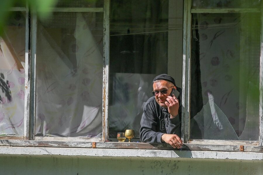 Ein älterer Mann schaut aus dem Fenster seiner Wohnung im schwer beschossenen Stadtteil Saltiwka in Charkiw. 