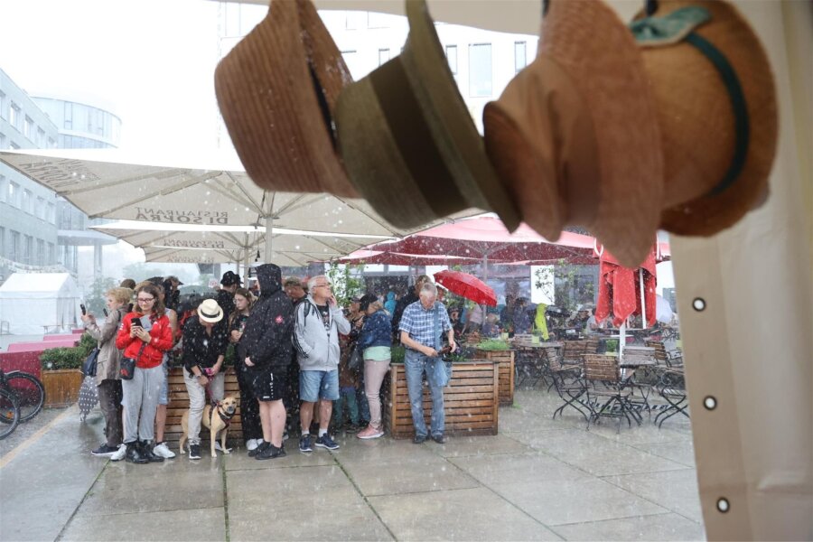 Chemnitzer Hutfestival wegen Gewitter mit Hagel unterbrochen - Leute suchen Unterschlupf. Wann das Hutfestival weitergeht, ist noch nicht bekannt.
