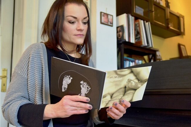 Stephanie Loos blättert in einem Fotoalbum, das eine Erinnerung an ihr Sternenkind Elise ist. Das Album hat die Chemnitzer Sternenkind-Fotografin Maika Maudrich angefertigt. 