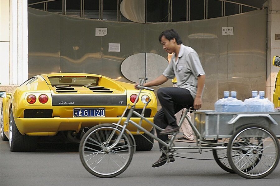 Kontraste in Peking: Ein Dreirad-Auslieferungsfahrer strampelt an einem Lamborghini vorüber, dessen Kaufpreis von über 200.000 Euro wohl seinem 200-fachen Jahreseinkommen entspricht. In Chinas Volkskongress sitzen viele Milliardäre und Multimillionäre, die jedes Jahr reicher werden. 
