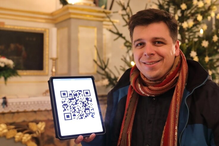 Digitales Anmelden für die Christvesper: Pfarrer Tobias Sommer - hier in der Grünhainer St.-Nicolai-Kirche - zeigt einen QR-Code. 