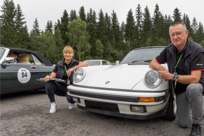Classic Rallye: Oldtimerbesitzer machen Station in Oberwiesenthal - Peter Weidinger, hier mit seiner Tochter Katja bei der Rallye 2021, ist auf der Starterliste zu finden. Der 64-Jährige Hormersdorfer - in der Motorsportszene kein Unbekannter - hatte vor zehn Jahren den Porsche Carrera 3.2 Targa, Baujahr 1988, gekauft. Weidinger ist Vorstandsmitglied für Sport beim ADAC Sachsen und seit Jahren in den Rallye-Starterlisten zu finden. Foto: Ronny Küttner/Archiv