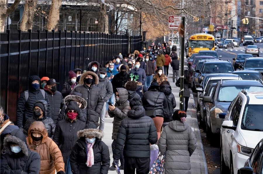 Eine lange Menschenschlange steht auf einem Gehweg im New Yorker Stadtbezirk Manhattan nach Coronatestkits an. 