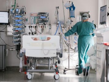 Corona in Sachsen: Noch 20 Kommunen über Inzidenz von 500 - Eine Pflegerin versorgt auf einer Intensivstation einen an Covid-19 erkrankten Patienten. 