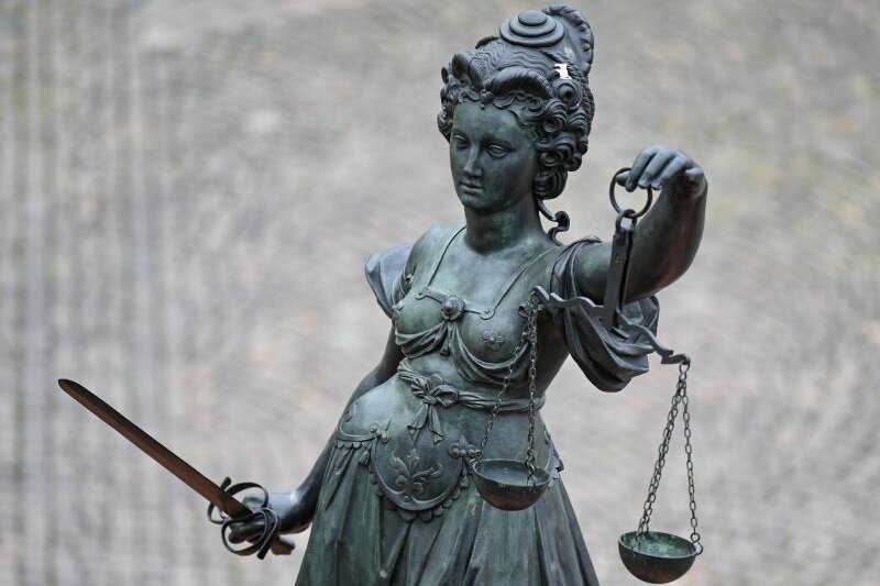            Die Statue der Justitia steht mit einer Waage und einem Schwert in der Hand.