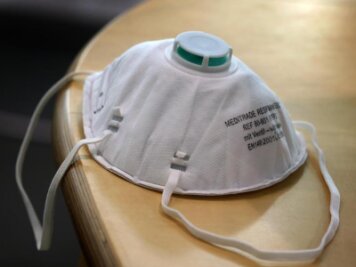            Eine FFP2-Atemschutzmaske liegt auf einem Tisch.