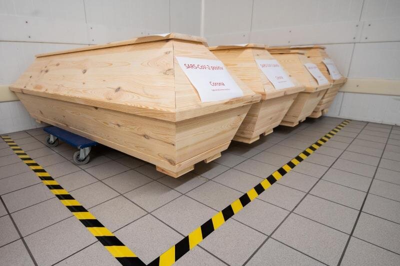            Särge mit der Aufschrift "SARS-CoV-2 positiv - Corona" mit Verstorbenen stehen in der Kühlkammer eines Krematoriums.