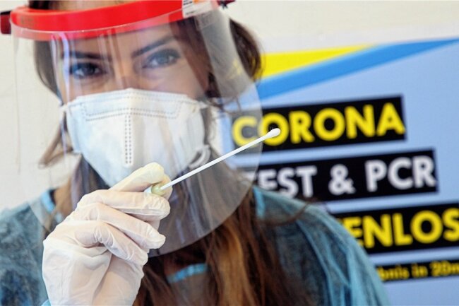 Corona-Testzentrum in Olbernhau zieht um - Eine Mitarbeiterin einer Corona-Teststelle posiert mit einem Teststäbchen für Corona-Schnelltest. Foto: Wolfgang Kumm/dpa