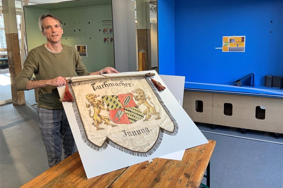 Crimmitschau: Museumsteam macht neugierig auf erste Dauerausstellung - Museumsleiter Philip Kardel zeigt eine Fahne der Crimmitschauer Tuchmacherinnung, die das Textilmuseum erst vor kurzem von der Restauratorin zurückbekommen hat.
