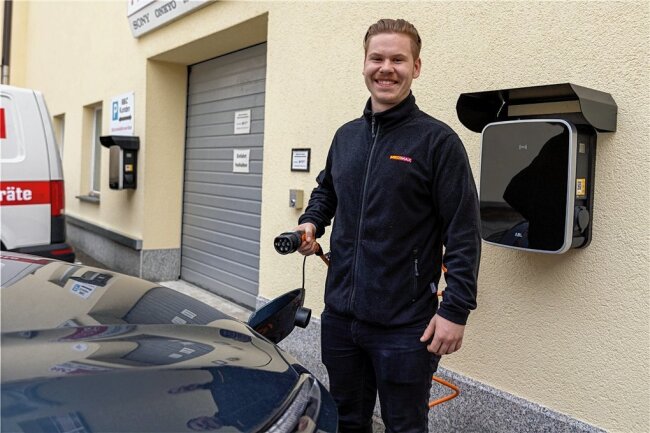 Dank Sonne: Auerbacher Unternehmer erzeugt ein Drittel des Strombedarfs künftig selbst - Medimax-Mitarbeiter Domenic Wunderlich macht gut gelaunt vor, wie es gehen könnte: Stecker rein, Strom ins E-Auto fließen lassen, wieder losfahren. 