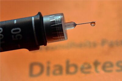 Das isolierte Insulin - Aus der Neuzeit: Ein Tropfen Insulin hängt an der Nadel einer Spritze für Diabetiker.