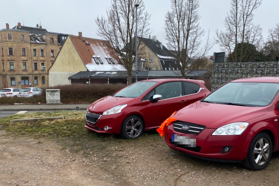 Der rote Peugeot und der rote Kia sind zwei der Autos, die augenscheinlich schon länger auf dem unbefestigten Parkplatz an der Kreuzung Oststraße/Dr.-Wilhelm-Külz-Straße/Frankenberger Straße stehen.