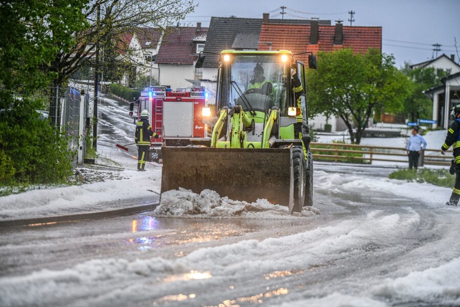 Dauerregen: Extreme Hochwassergefahr im Saarland - Einsatzkräfte der Feuerwehr räumen nach einem Hagelscheuer eine Straße in Söhnstetten im Landkreis Heidenheim (Baden-Württemberg).