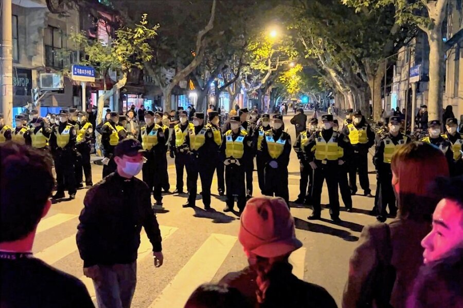 Demonstranten fordern: Nieder mit Xi, nieder mit der Partei - Chinesische Polizisten versperren den Zugang zu einem Platz, an dem sich Demonstranten versammelt hatten. In China hat die strenge Coronapolitik zu den größten Protesten seit Jahrzehnten geführt.