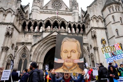 Der Anfang vom Ende – Gericht berät über Assange-Auslieferung - Der Künstler Kaya Mar hält sein Gemälde von Julian Assange hoch, während Demonstranten vor dem Londoner High Court die Freilassung des Wikileaks-Gründers fordern.