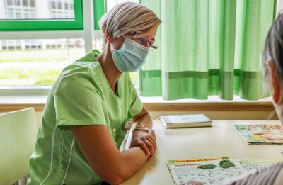 Der Besuch der Grünen Dame - Die Grüne Dame Stefanie Jahr lässt sich im Krankenzimmer von Patientin Renate Baum ein Rätselheft erklären. 