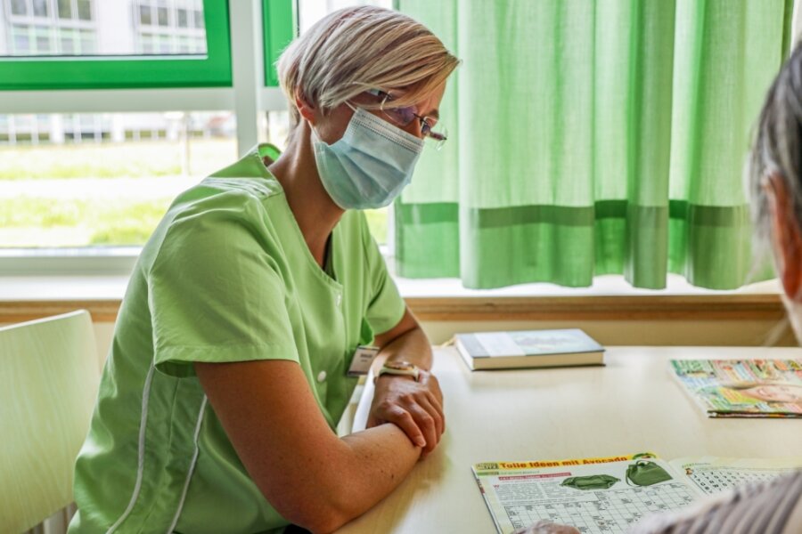 Der Besuch der Grünen Dame - Die Grüne Dame Stefanie Jahr lässt sich im Krankenzimmer von Patientin Renate Baum ein Rätselheft erklären. 