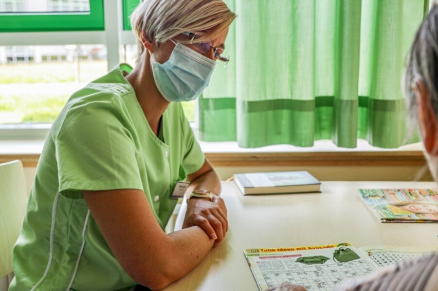 Der Besuch der Grünen Dame - Stefanie Jahr lässt sich im Krankenzimmer von Patientin Renate Baum ein Rätselheft erklären. 