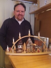 Der Häuselmacher mit den goldenen Händen - Roman Naumann mit seinem neuesten Modell, einem Schwibbogen. Auf ihm ist ein erzgebirgischer Markt zu sehen. 