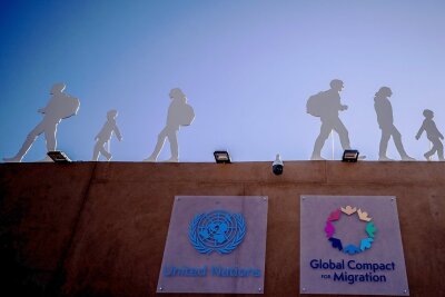Der Pakt im Sand - Pakt für 285 Millionen Menschen: Der Aufsteller mit Silhouetten von Migranten weist auf die UN-Konferenz in Marrakesch hin.