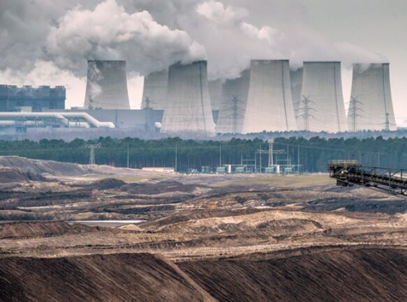 Der schwere Ausstieg aus der Braunkohle - Verzichtbar? Blick über Abraumhalden des Jänschwalder Braunkohletagebaus auf die Kühltürme des Kraftwerks der Vattenfall AG.