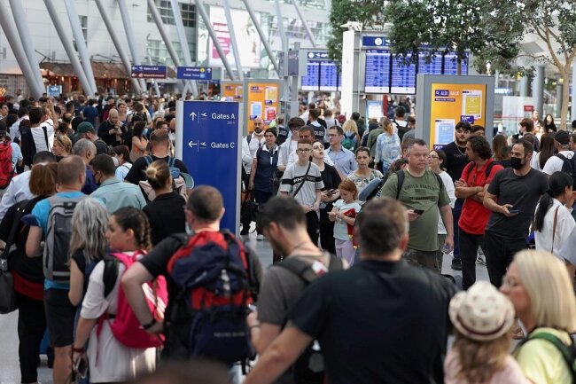Passagiere stehen Schlange im Flughafen Düsseldorf. Der Ferienstart im bevölkerungsreichsten Bundesland Nordrhein-Westfalen dürfte am Wochenende zu stundenlangen Wartezeiten beim Check-in und an den Sicherheitskontrollen führen. 