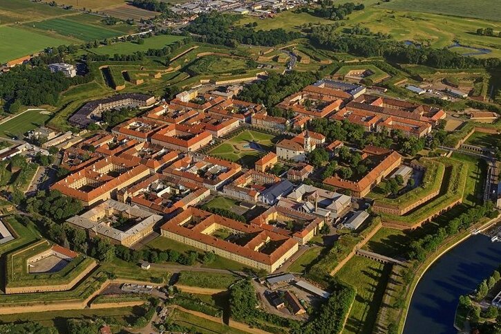 Festung und Stadt Terezín in einer Luftaufnahme: ein Platz sowie neun Längs-und sechs Querstraßen mit Kasernen- und Wohngebäuden, umgeben von mächtigen Wallanlagen und Bastionen.