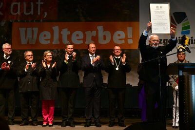 Die Montanregion Erzgebirge ist offiziell Welterbe - Alt-Landrat Volker Uhlig hält stolz die Welterbe-Urkunde in die Höhe.