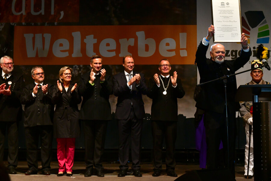 Die Montanregion Erzgebirge ist offiziell Welterbe - Alt-Landrat Volker Uhlig hält stolz die Welterbe-Urkunde in die Höhe.
