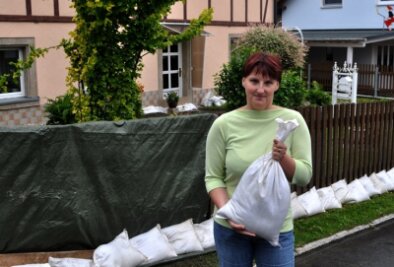 Die Nerven liegen blank - Yvonne Schumann vor ihrem Haus: Am Dienstag wurde eine Barriere aus Sandsäcken am Zaun aufgeschichtet.