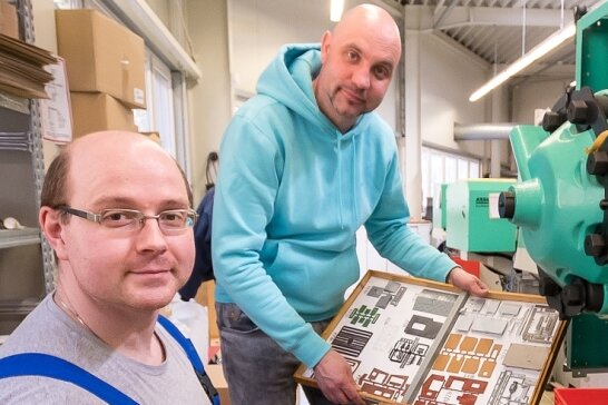 Geschäftsführer Markus Hillig (rechts) kontrolliert mit Mitarbeiter Maik Reichel an einer der Spritzgussmaschinen gefertigte Bauteile. Sie bilden das Modell eines Sägewerks.